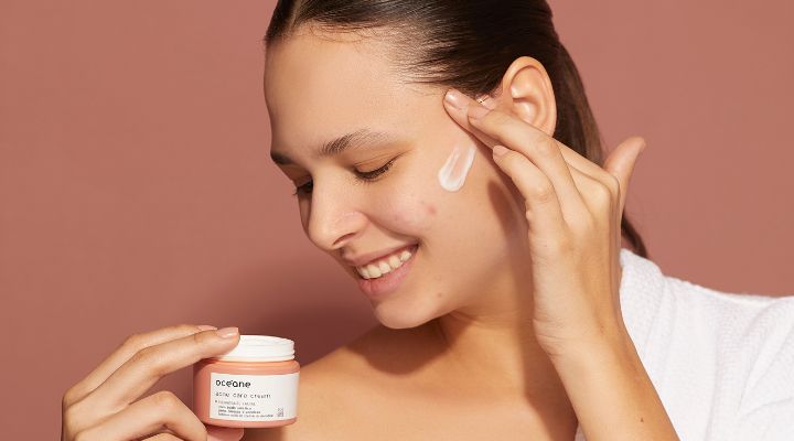 Mulher aplicando creme facial com sorriso