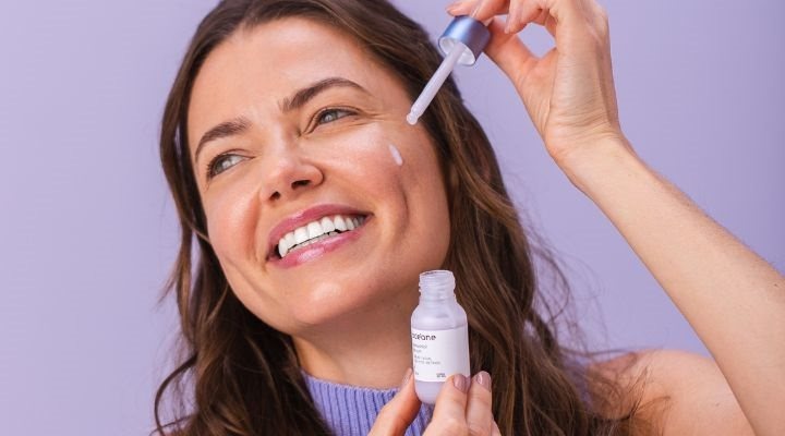 Mulher sorrindo e passando o sérum facial com fito-retinol Océane no rosto