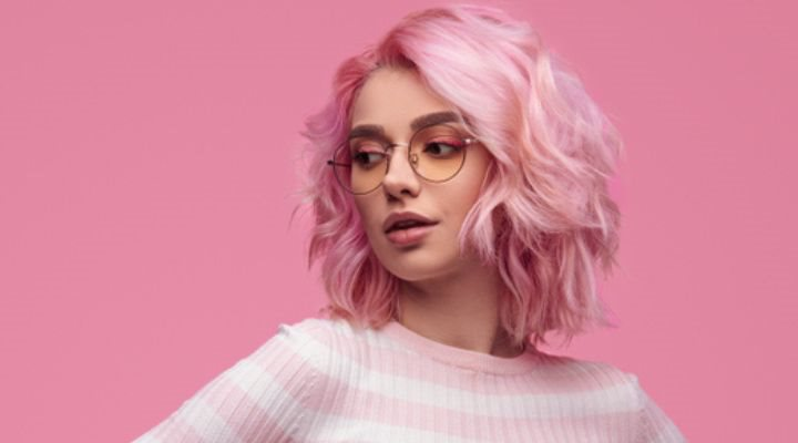 Modelo de cabelo rosa curto posando em um fundo cor-de-rosa