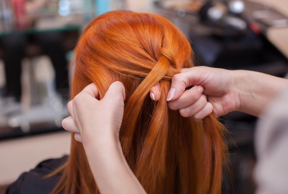 Cabeleireira fazendo trança em modelo ruiva