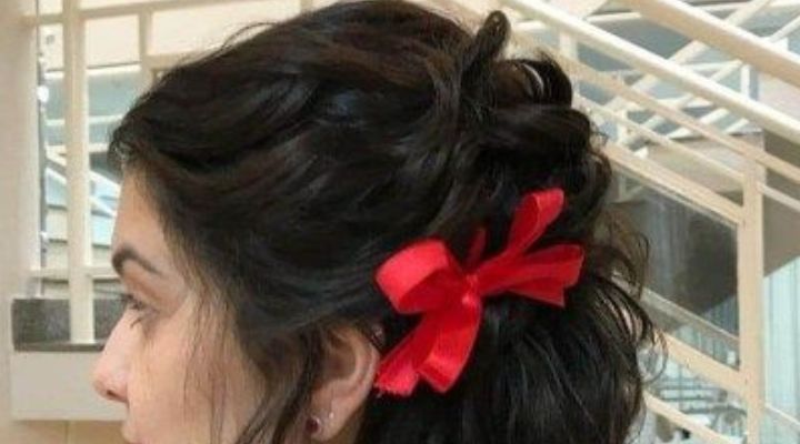 Modelo de cabelo-castanho usando trança solta presa com laço vermelho