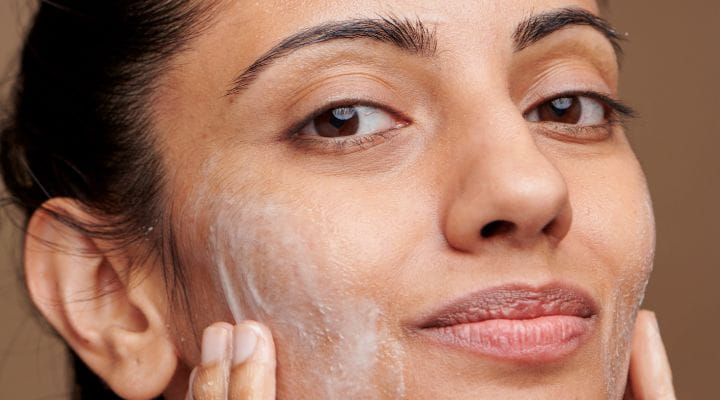 Foto de uma mulher com uma solução de skincare no rosto. 