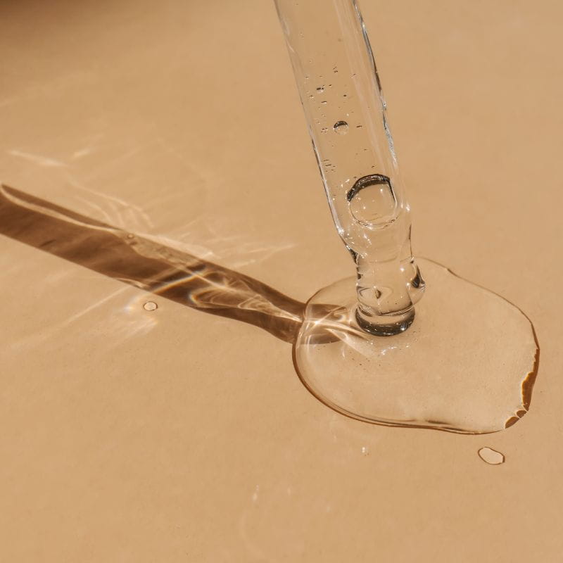 Imagem de um aplicador de sérum derramando o líquido em uma superfície.