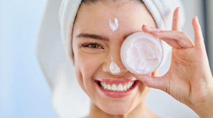 Mulher sorrindo segurando um creme hidratante facial da oceane