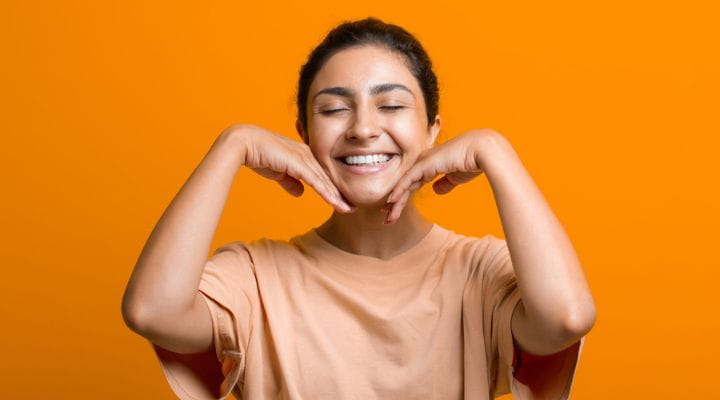 Foto de uma modelo realizando o movimento v do yoga facial, com as mãos em formato de V na mandíbula.