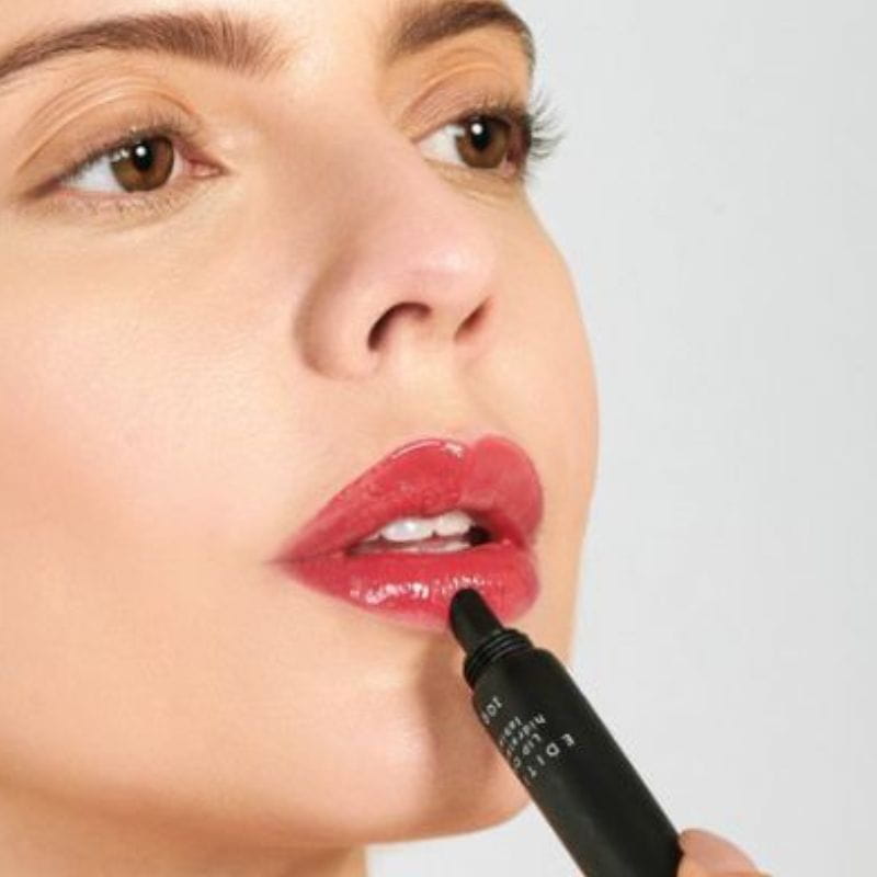 Foto de uma mulher usando o lip oil da linha Edition Océane.