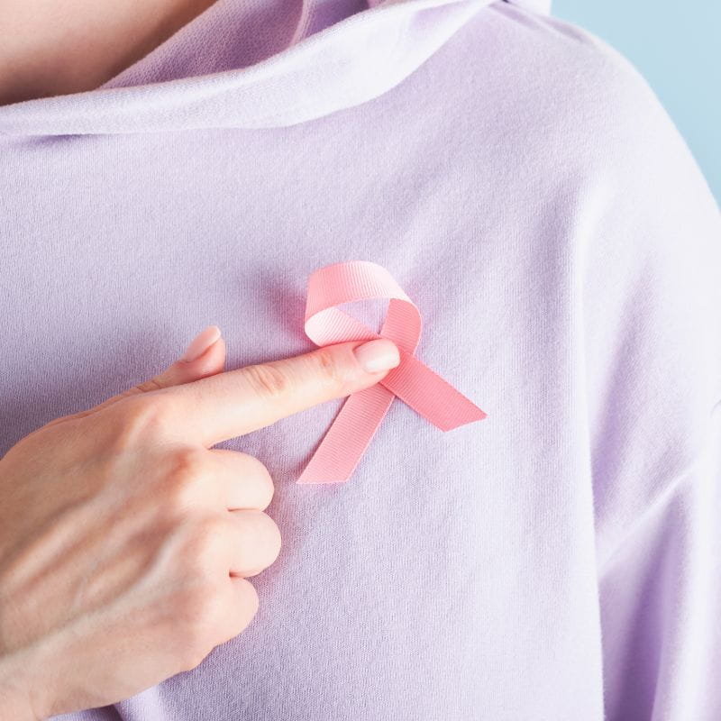 Foto de uma modelo com o laço rosa do outubro rosa em sua camiseta.