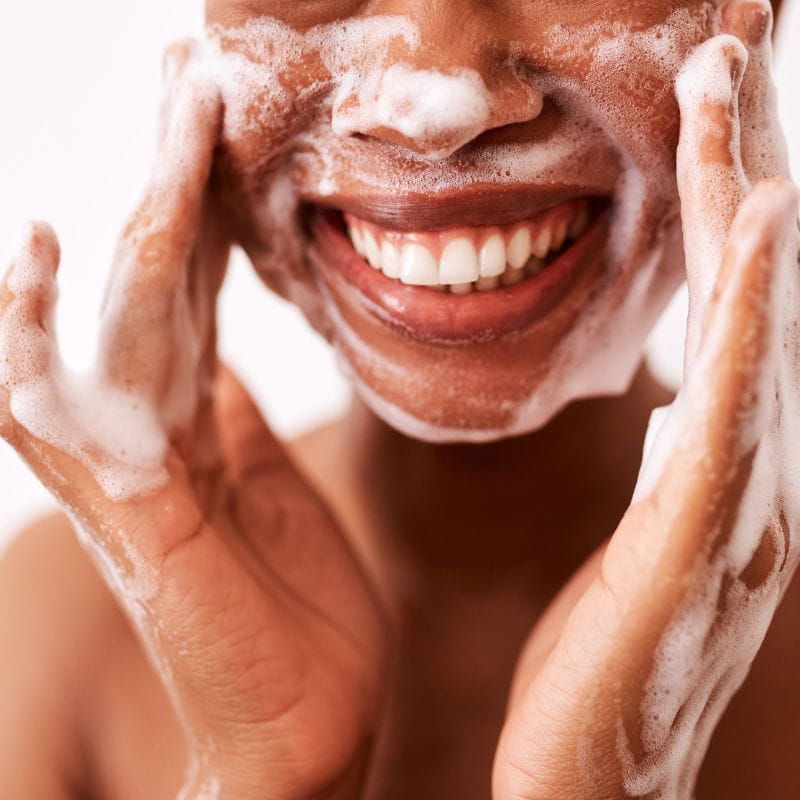 Modelo realizando uma limpeza facial com a tecnica do double cleansing.