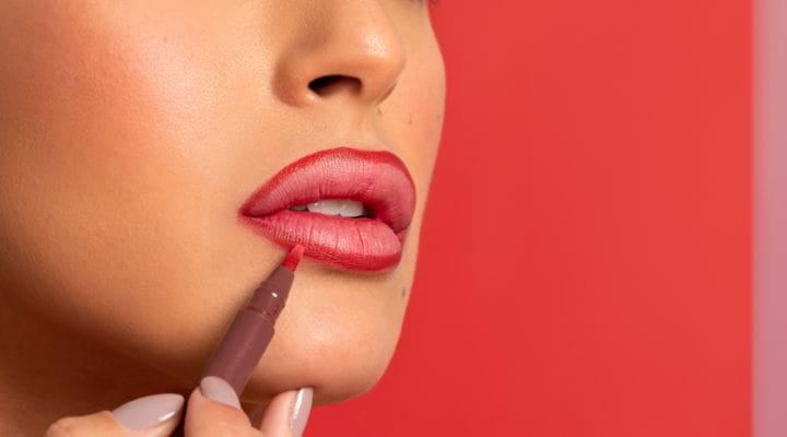 modelo aplicando contorno labial vermelho nos lábios 