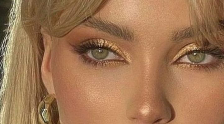 modelo loira com olhos verdes com maquiagem dourada