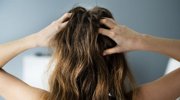 mulher de costas segurando o cabelo com as duas mãos