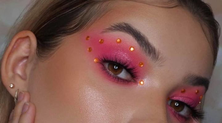 Modelo com maquiagem rosa e pedras laranjas coladas no côncavo