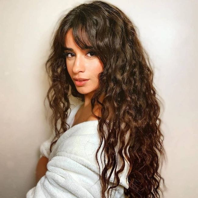 Artista Camila Cabello posando com seu cabelo ondulado longo