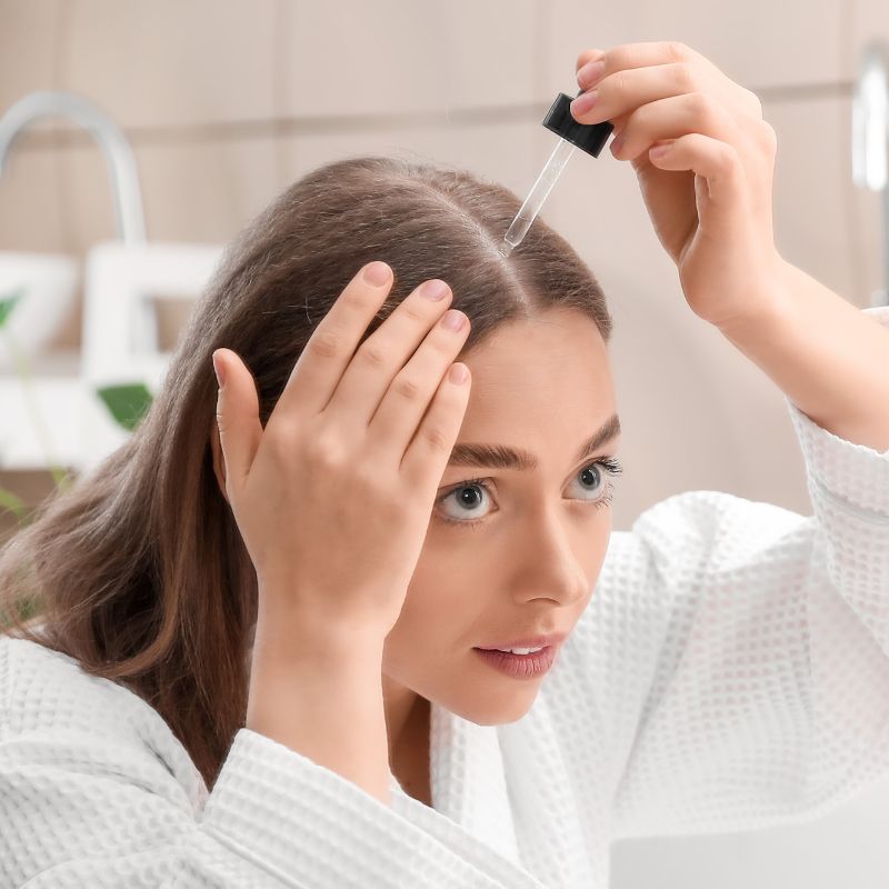mulher aplicando minoxidil no couro cabeludo