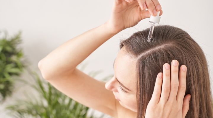 mulher aplicando minoxidil no couro cabeludo