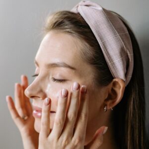 mulher aplicando creme para skincare no rosto