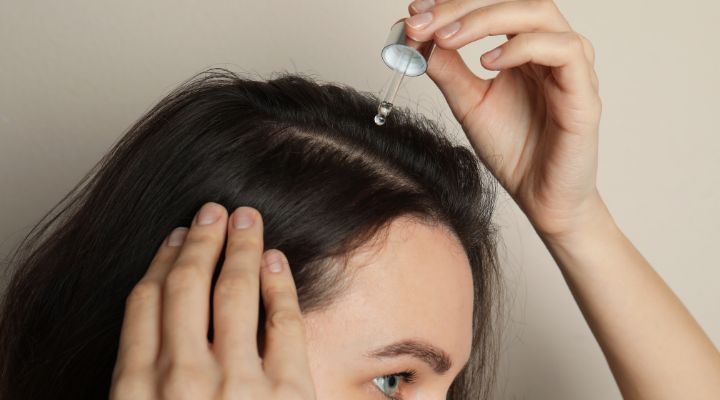 mulher aplicando óleo de argan no cabelo