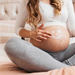 mulher grávida passando creme na barriga