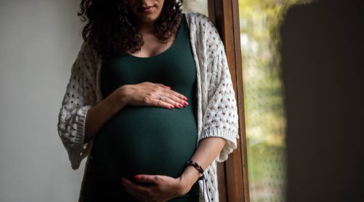 gravida de verde segurando a barriga