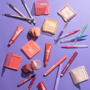 varios produtos de maquiagem dispostos sobre um fundo roxo