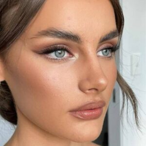 Rosto de mulher com maquiagem nos olhos e pele iluminada.