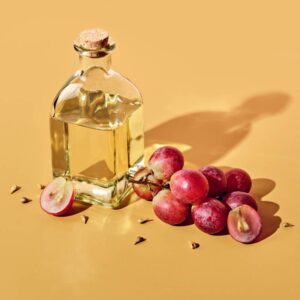 Garrafa de óleo de semente de uva com uvas e sementes.