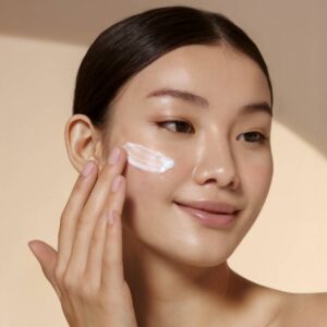 modelo passando hidratante no rosto