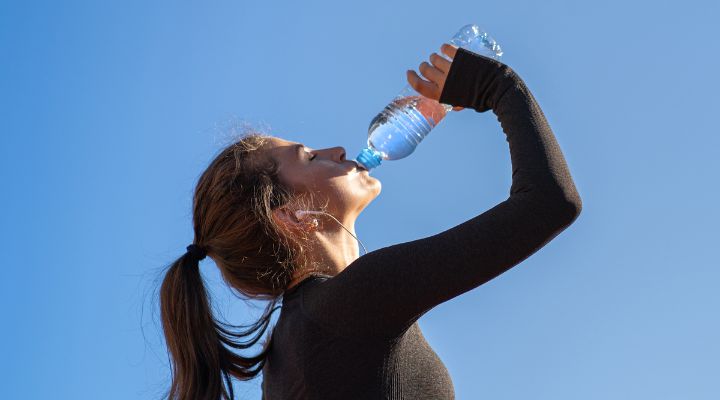 Mulher bebendo água em dia ensolarado