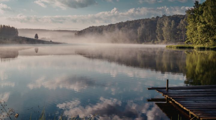Lago sereno com neblina ao amanhecer