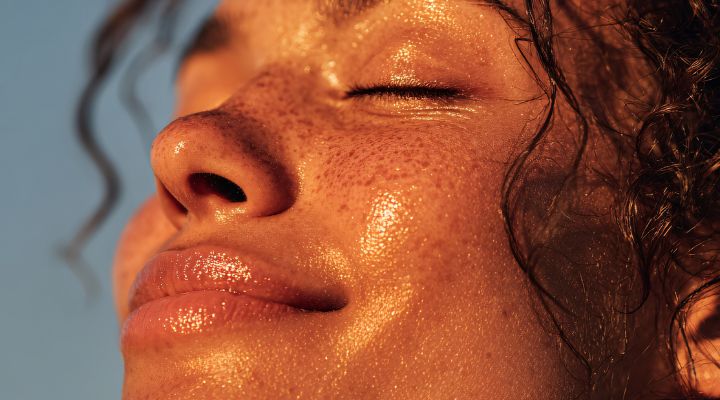 Mulher com pele iluminada e sorriso ao sol