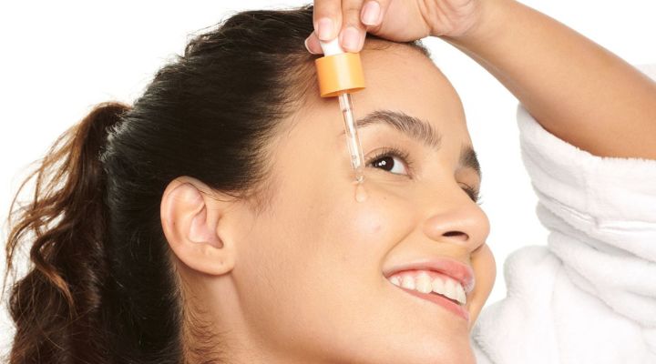 Mulher aplicando sérum facial com conta-gotas