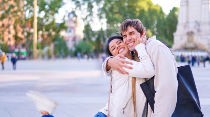 Um casal sorridente se abraçando ao ar livre.