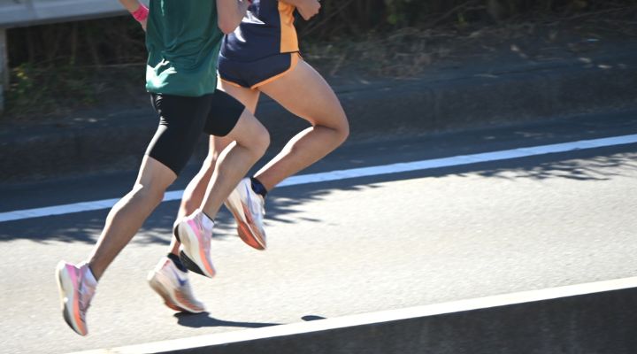 Dupla correndo na pista, foco nas pernas em movimento.