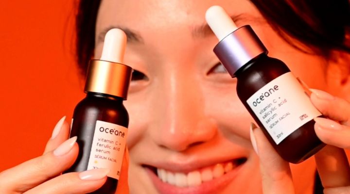 Mulher segurando frascos de sérum facial e sorrindo