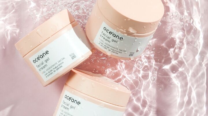 Três potes de gel facial Oceane sobre água rosa.