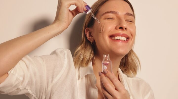 Mulher aplicando sérum facial com conta-gotas
