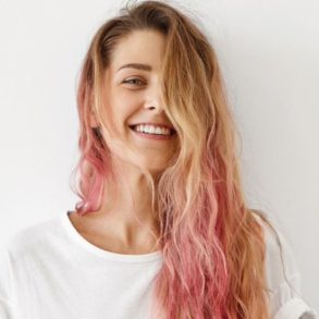 Mulher loira de cabelo ondulado com mechas cor-de-rosa nas pontas