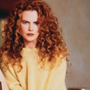 Nicole Kidman posando com cabelo ondulado volumoso e blusa amarela de manga longa