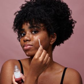 modelo passando o secativo de espinhas em sua maça do rosto