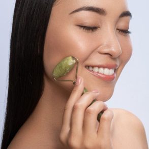 modelo passando o rolinho de skincare em seu rosto