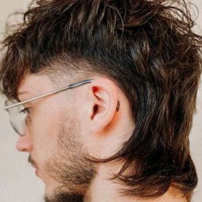 perfil de um homem com cabelo corte tipo mullet, raspado nas laterais e comprido no restante.
