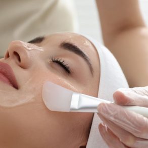 Foto de uma mulher realizando o procedimento estético de peeling facial.